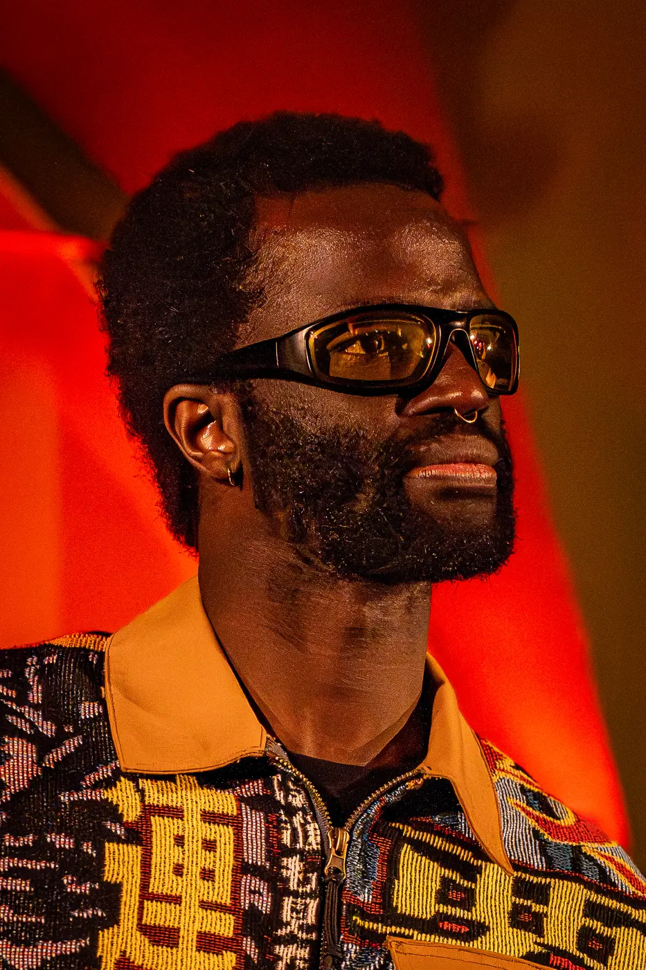 Portrait de Koeurbo, lunettes de soleil et veste à motifs, regard de profil